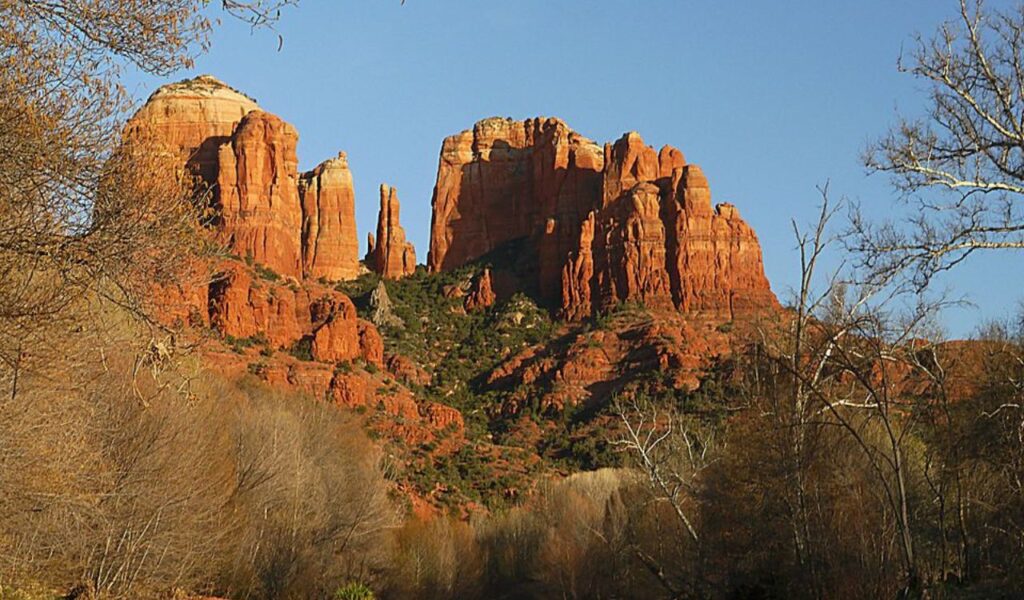Cathedral Rock in Sedona, Arizona, with red rock formations and trees under a clear blue sky.