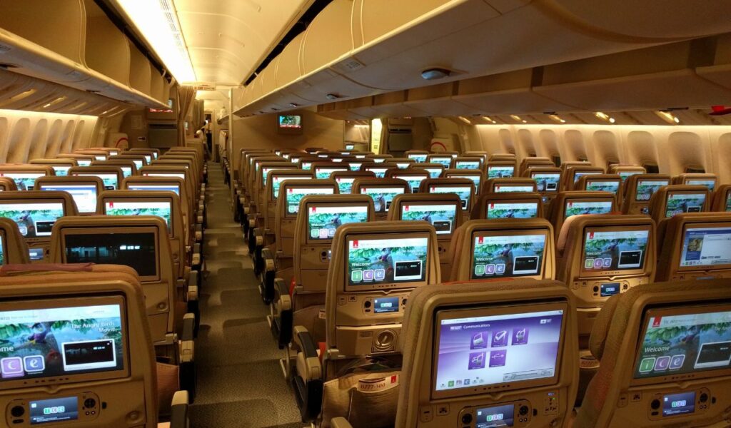 Empty economy class cabin with entertainment screens ready, highlighting full service availability and a well-prepared flight experience.