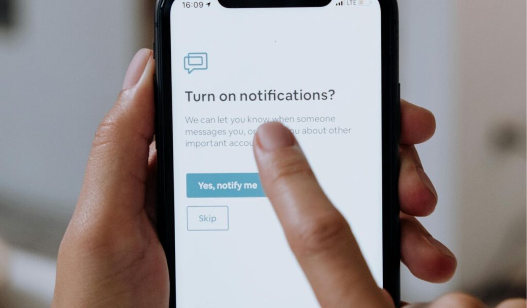 Person tapping on a smartphone screen to enable travel deal notifications and price alerts for flights.