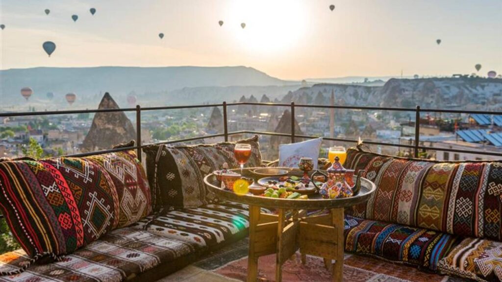 Traditional turkish breakfast with Cappadocia view and flying balloons on the background. Goreme, Turkey.