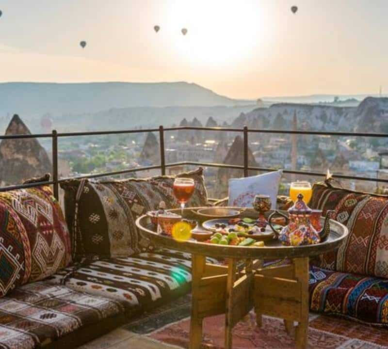 Traditional turkish breakfast with Cappadocia view and flying balloons on the background. Goreme, Turkey.