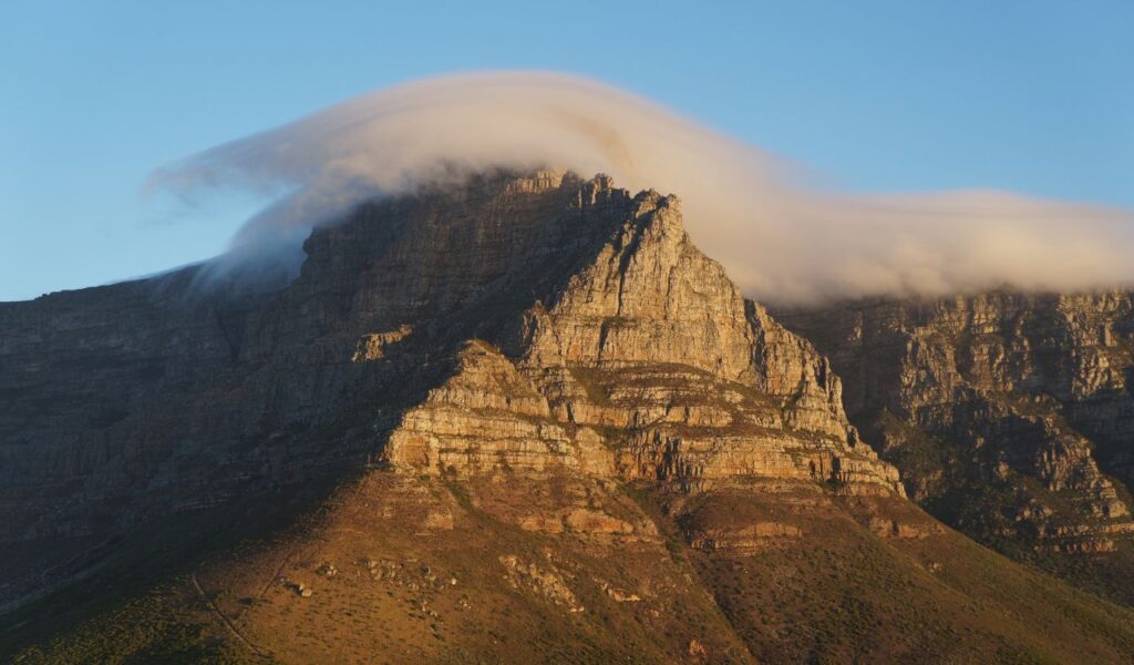 Table Mountain in Cape Town, South Africa, with clouds rolling over its summit, creating a dramatic natural effect.