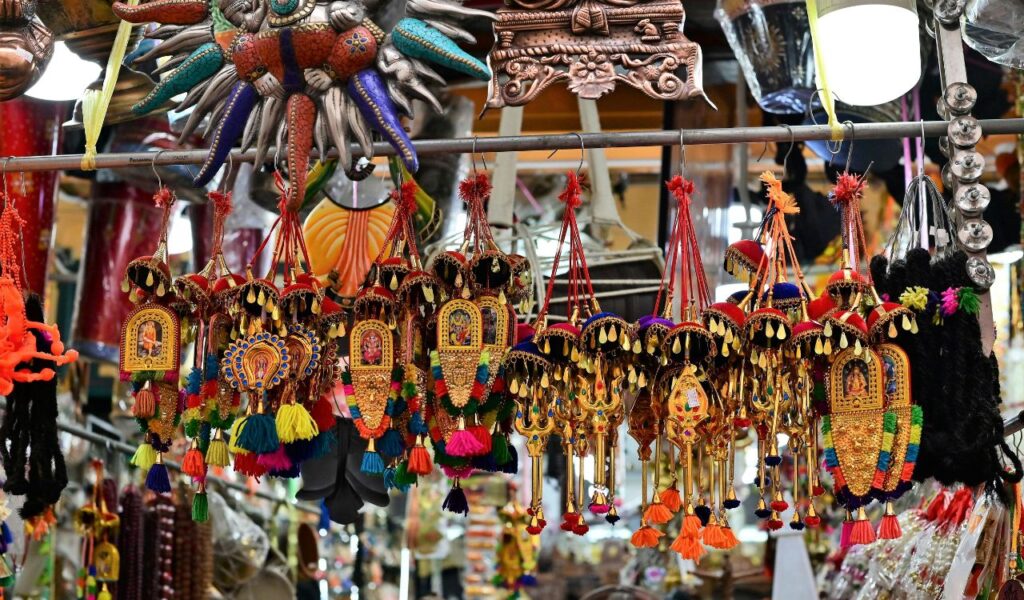 Colorful hanging souvenirs and trinkets displayed in a busy market stall, showcasing intricate designs, tassels, and vibrant decorations.