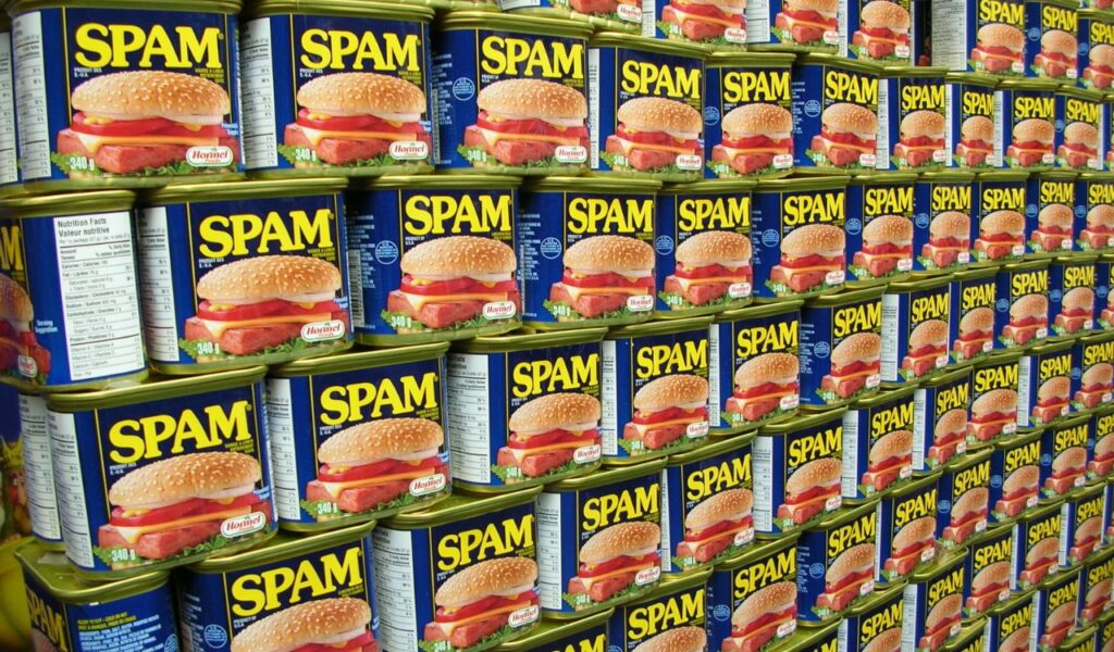 A display of neatly stacked Spam cans featuring the iconic blue label and a hamburger image on each can.