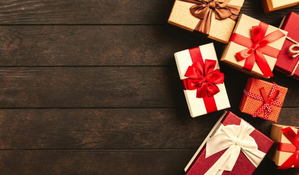 Several gift boxes wrapped in festive paper and ribbons arranged on a dark wooden surface, ready for celebration.