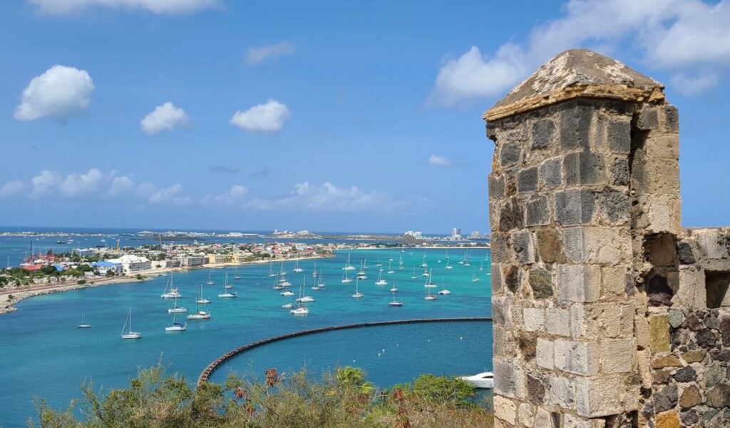 Scenic view of sailboats in turquoise waters near the coast of St. Martin, seen from an old stone lookout.