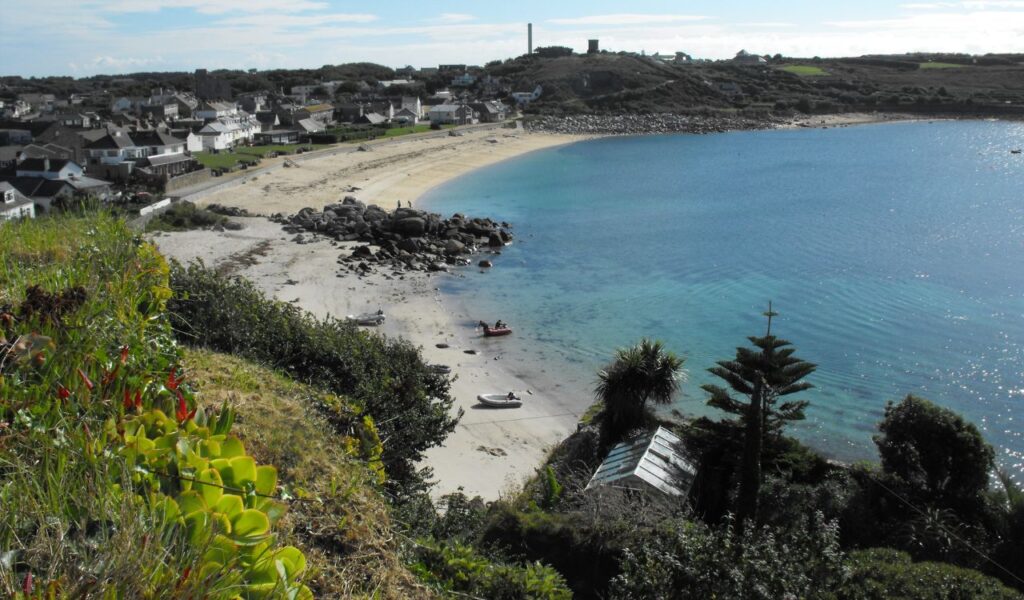 Coastal view near St. Mary’s Space on the Isle of Skye, with clear waters, sandy beach, and scattered cottages in the distance.