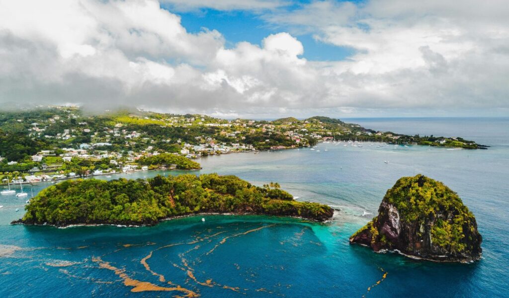 Aerial view of St Vincent with lush green islets, turquoise waters, and coastal towns tucked into the hillside.