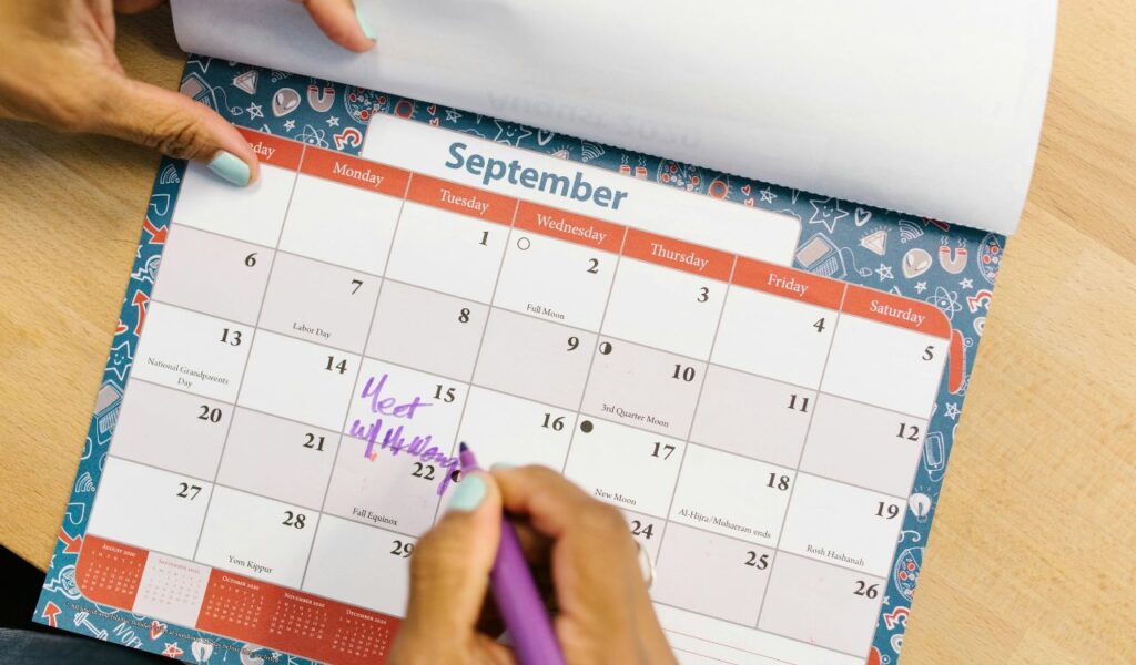 Hand writing on a colorful September calendar, highlighting flexible travel planning with marked dates and notes.