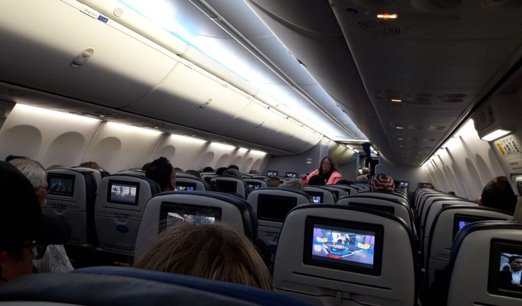 Passengers in economy class enjoying in-flight entertainment, creating a calm and positive travel experience.