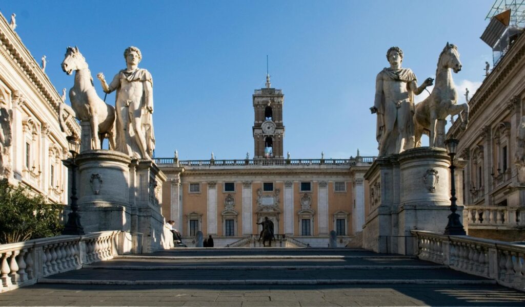 Capitoline Hill in Rome, with grand staircase flanked by statues, leading to the Palazzo Senatorio and clock tower.