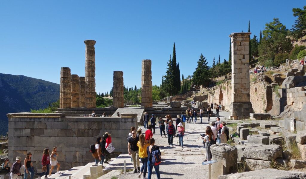 Tourists exploring ancient ruins on a sunny day, representing guided tours or activity add-on costs during travel.