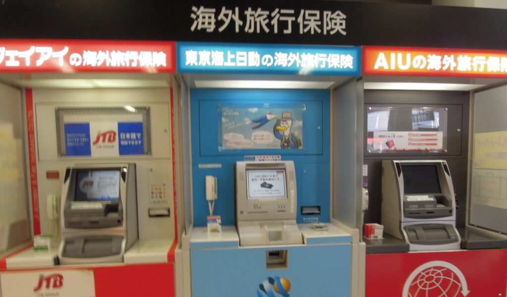Travel insurance kiosks with screens and signage in Japanese, highlighting the importance of coverage while abroad.