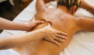 Person receiving a relaxing back massage at a spa, promoting stress relief and therapeutic relaxation.