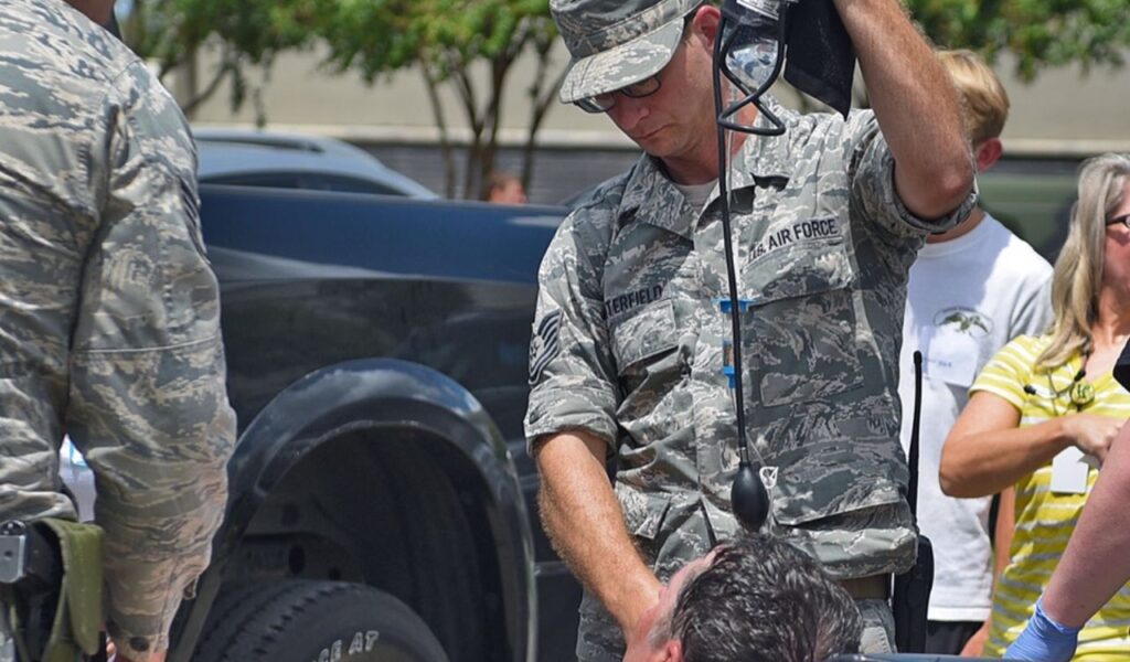 U.S. Air Force personnel assisting a person showing signs of heat illness, highlighting heat exhaustion response.