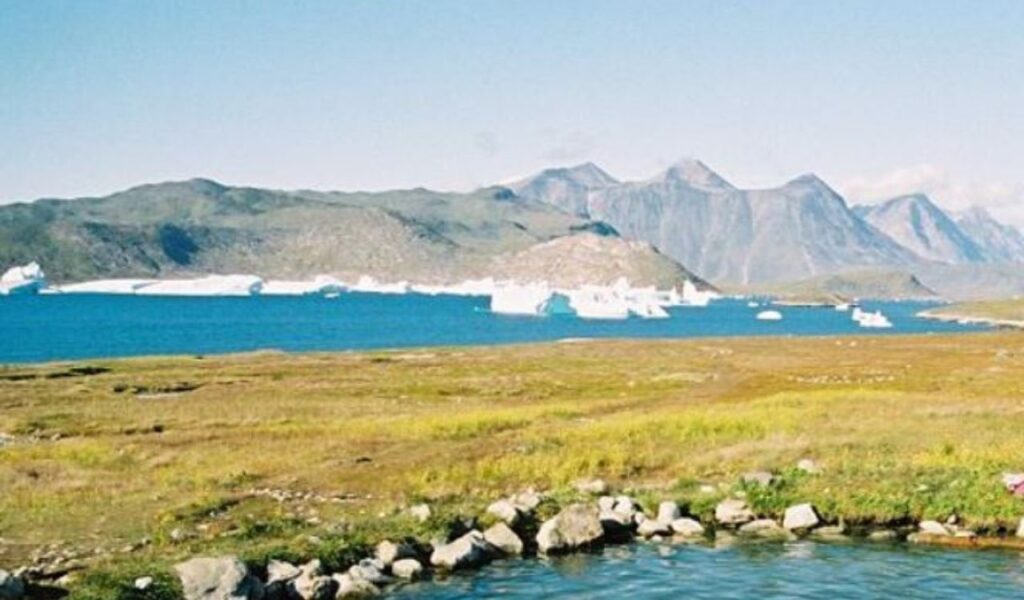 Uunartoq Hot Springs in Greenland, featuring pristine waters surrounded by rugged landscapes and towering mountains.