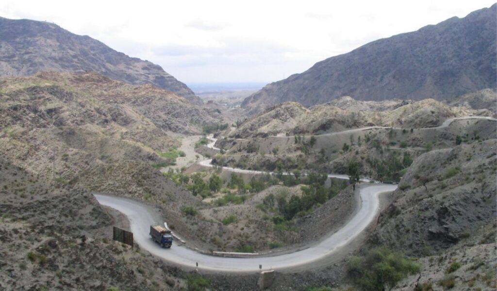 Truck navigating a winding mountain road through the scenic Khyber Pass, highlighting the need to focus on the road.