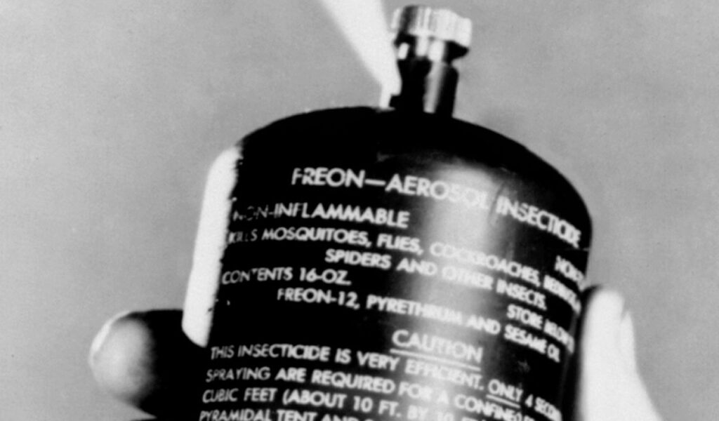 Close-up of an old aerosol insecticide can being sprayed, labeled with worn text and visible signs of age.