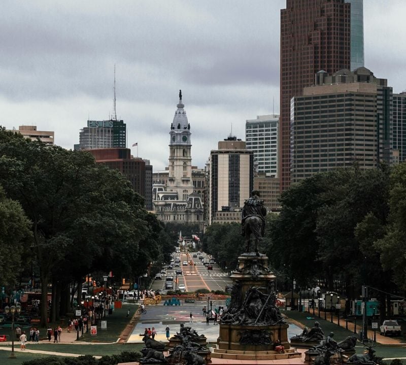 View of Philadelphia’s skyline from the art museum steps, with City Hall in the distance and a historic fountain in the foreground.