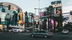 Lively Las Vegas Strip intersection with cars, palm trees, bright signs for Marshalls and MGM, and colorful M&M character statues.