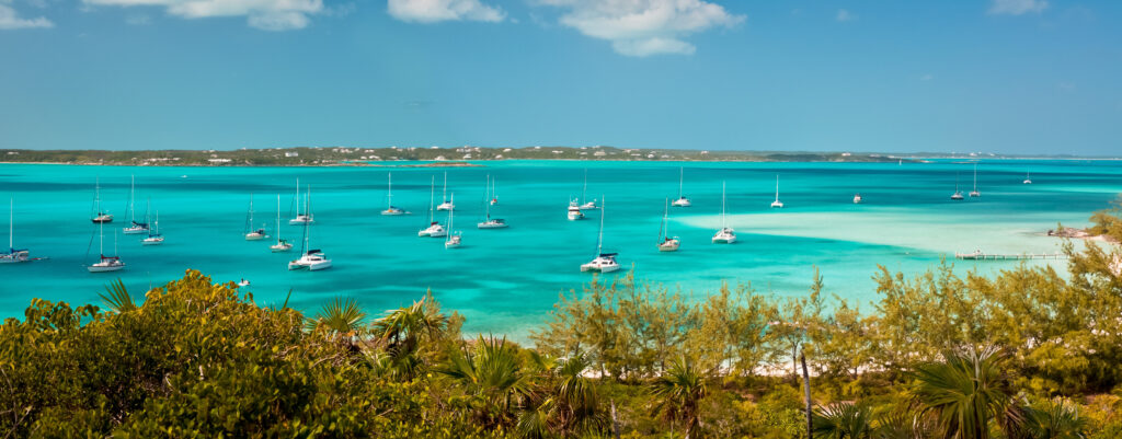 panoramic image of the harbour, or anchorage, in the bahamas near George Town in the Exumas Sand bar with small boat dock is off to the right and copy space is available in the clear blue sky