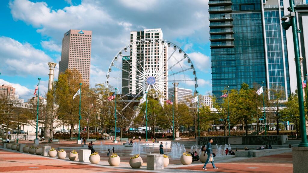 A bright day in downtown Atlanta, Georgia, with people enjoying Centennial Olympic Park, fountains, and the towering SkyView Ferris wheel.