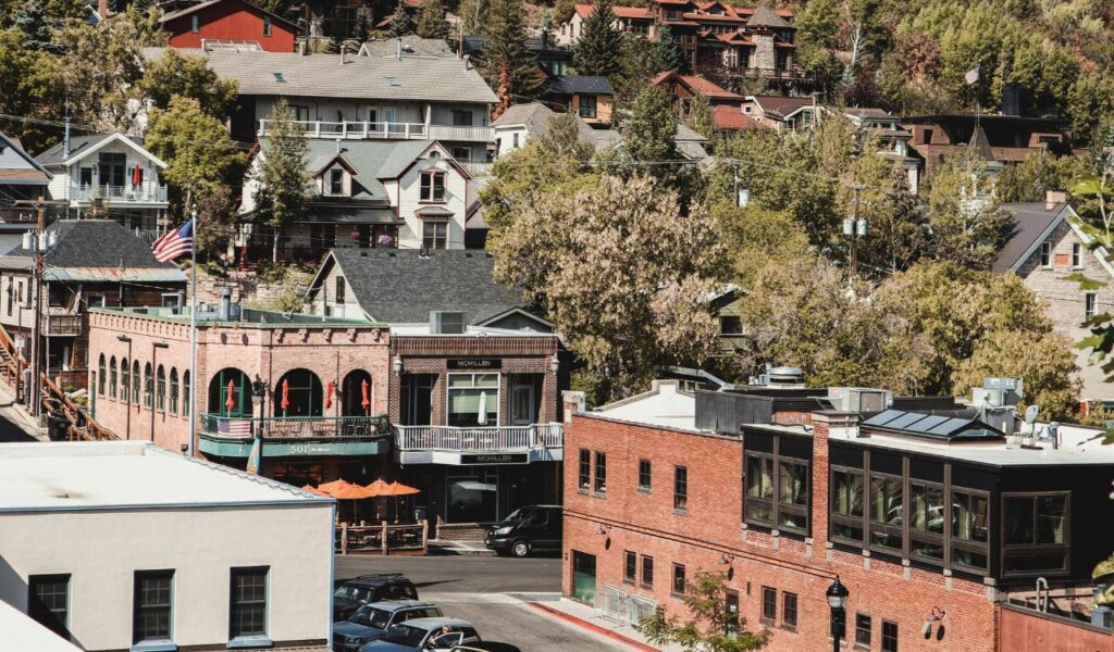 Historic Bisbee, Arizona, with red-brick buildings, colorful hillside homes, and tree-lined streets under a sunny, clear sky.