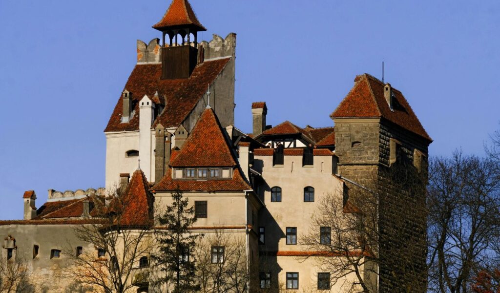 Bran Castle in Romania with red rooftops and historic stone walls under a clear blue sky