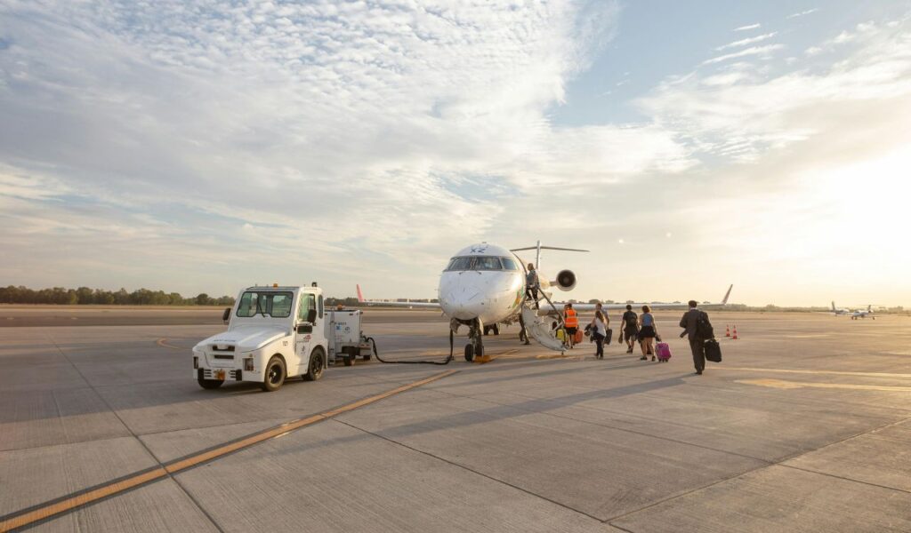 Passengers walking across the tarmac to board a small budget airline plane, highlighting hidden airport inconveniences.