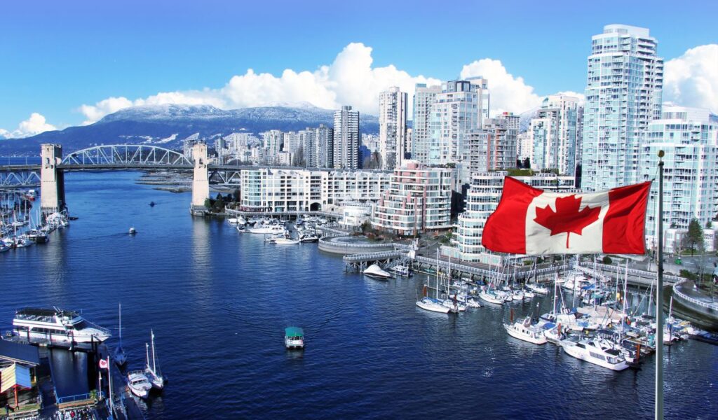 Canadian flag in front of view of False Creek and the Burrard street bridge in Vancouver, Canada.