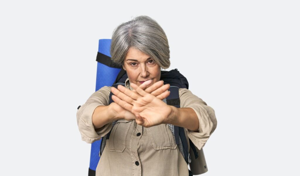 Caucasian mid-age female with hiking gear doing a denial gesture