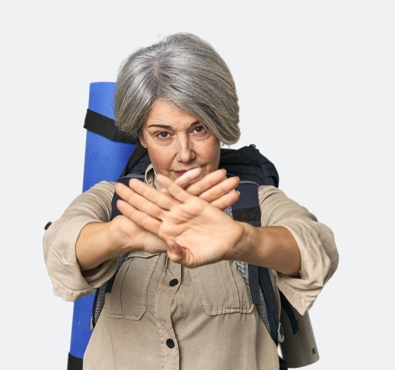 Caucasian mid-age female with hiking gear doing a denial gesture