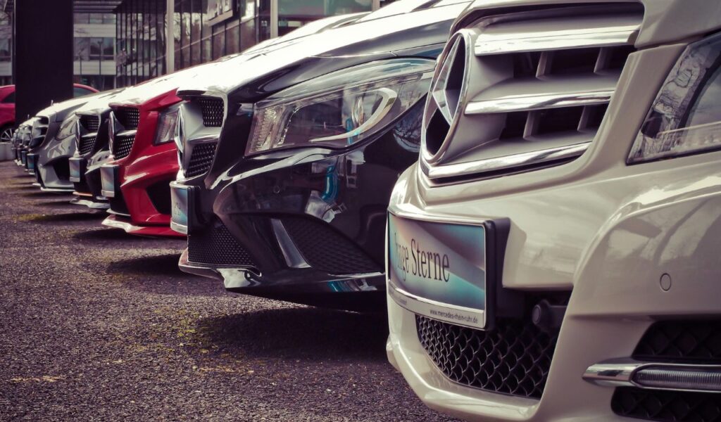 Row of modern rental cars parked in a lot, showcasing shiny grilles and headlights, symbolizing hidden rental costs