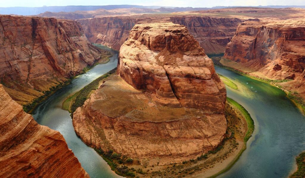 A breathtaking view of Horseshoe Bend in the Grand Canyon, showcasing the Colorado River curving around red rock cliffs under a clear sky.