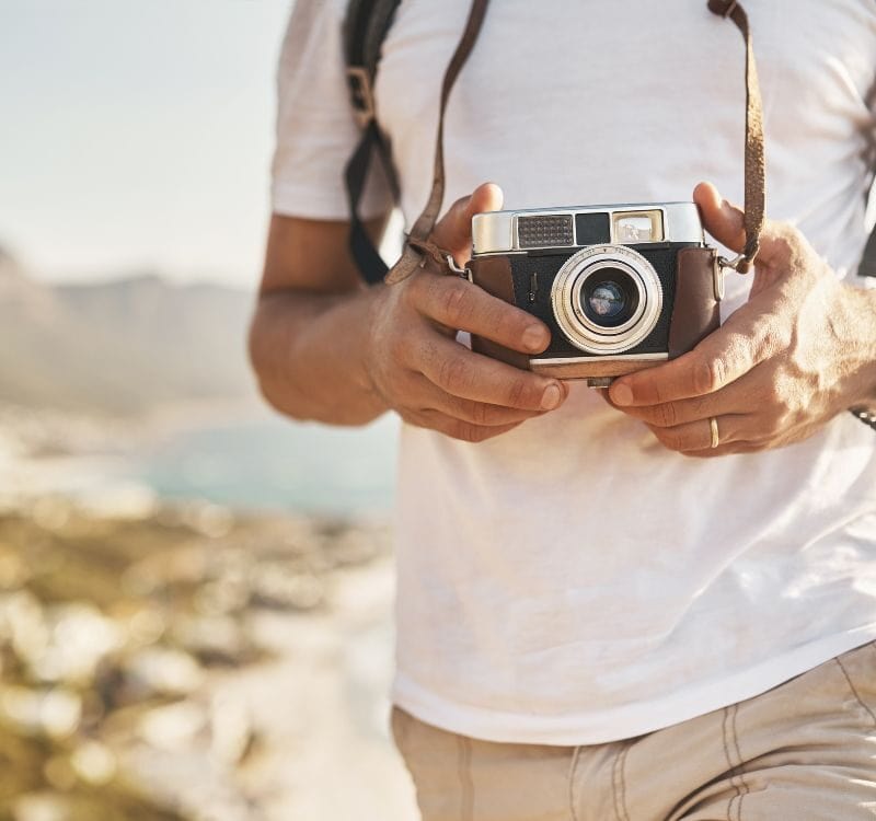 His camera goes wherever he goes. an unrecognizable man hiking with his camera in the mountains.
