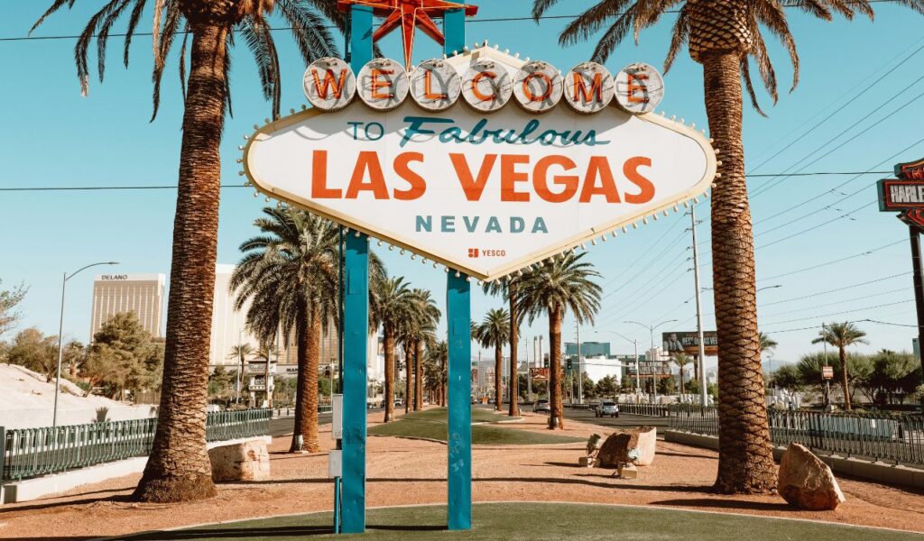 The iconic 'Welcome to Fabulous Las Vegas' sign in Nevada, surrounded by palm trees and clear blue skies, with hotels visible in the background
