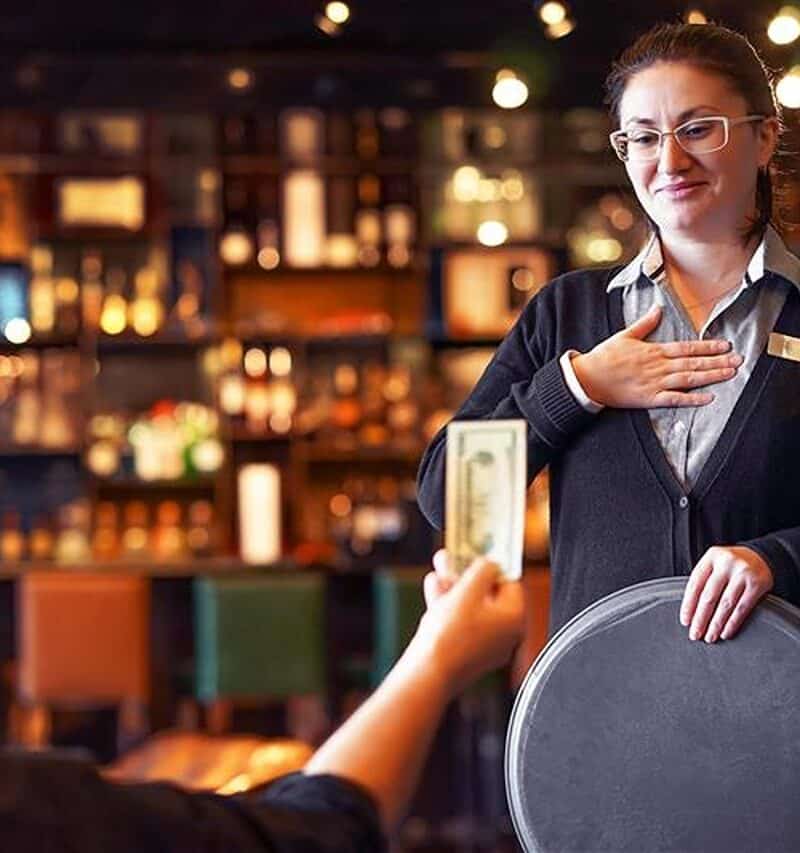 Waitress takes the tip. The waiter female receives a tip from the client at the hotel bar. The concept of service