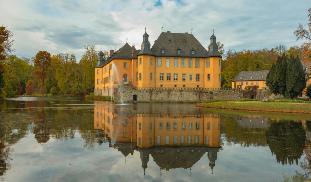 Mespelbrunn Castle in Germany reflected in the calm waters of a surrounding lake.