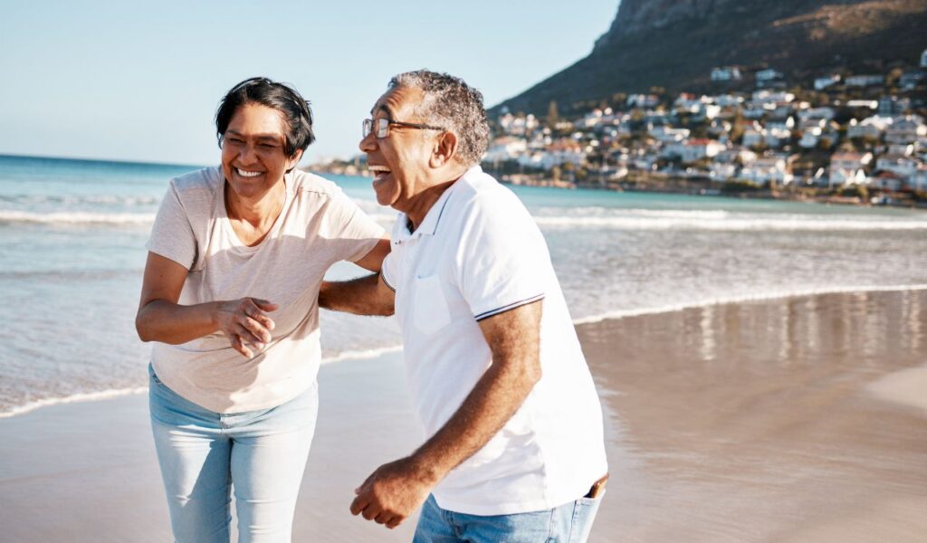 Outdoor laughing and senior couple at beach for happiness funny joke or summer getaway trip ocean married woman and elderly man