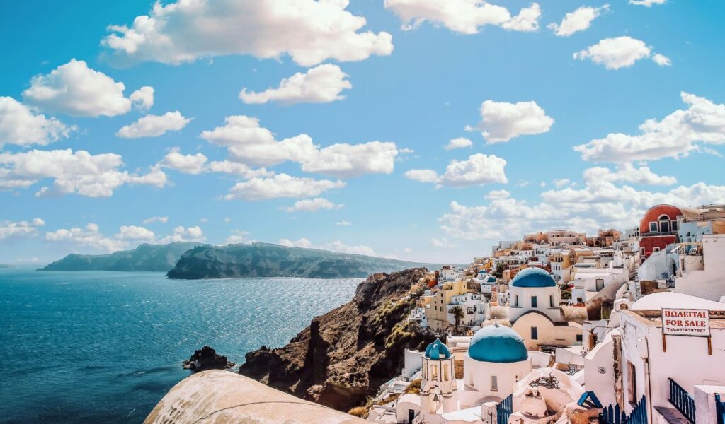 Scenic view of Santorini’s whitewashed houses with blue domes overlooking the Aegean Sea, a popular tourist destination