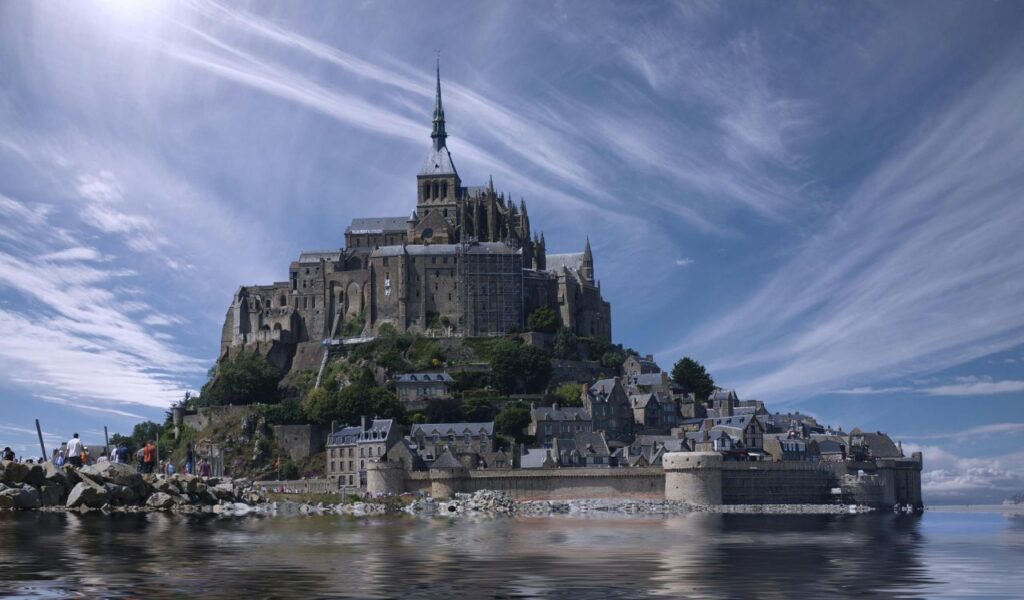 Mont Saint-Michel in France, rising dramatically from the sea with its towering abbey, medieval stone walls, and quaint village buildings below.