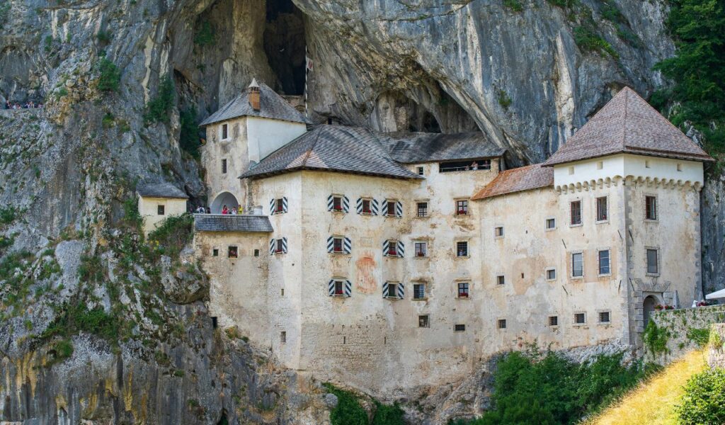 Predjama Castle in Slovenia built into a rocky cliffside with its stone walls blending seamlessly into the cave behind it.