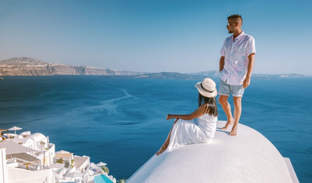 Santorini Greece, a young couple on luxury vacation at the Island of Santorini and whitewashed village of Oia Santorini