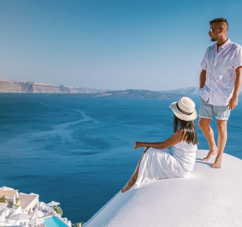 Santorini Greece, a young couple on luxury vacation at the Island of Santorini and whitewashed village of Oia Santorini