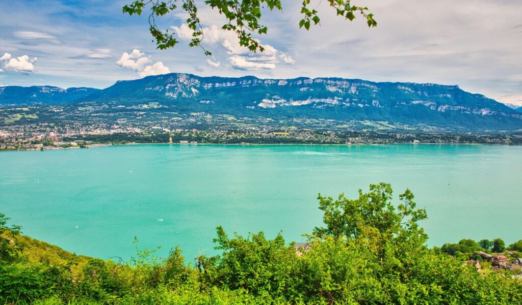 Turquoise lake stretches across the valley beneath the blue ridgeline of Savoy Mountain on a sunny afternoon.