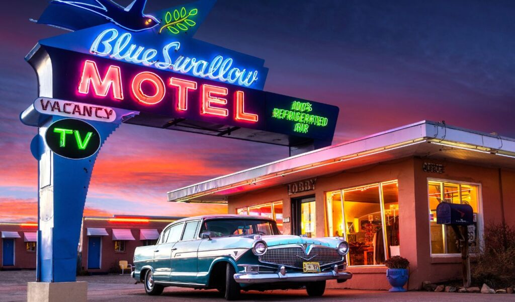 Tucumcari, NM - USA - March 16 2022 Historic Blue Swallow Motel on Route 66 with Neon and Classic Car at Sunset.