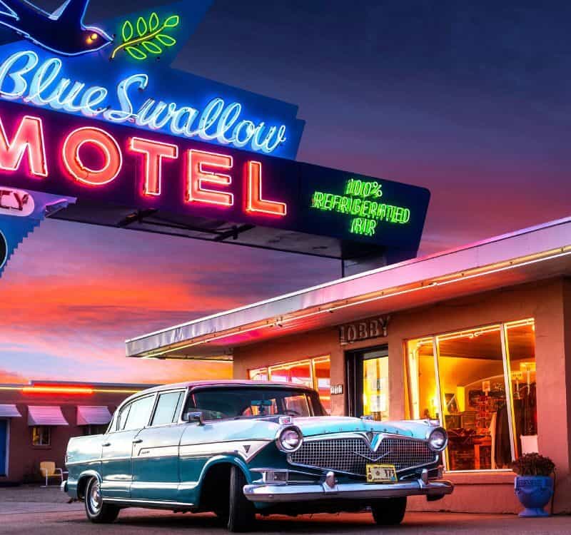 Tucumcari, NM - USA - March 16 2022 Historic Blue Swallow Motel on Route 66 with Neon and Classic Car at Sunset.