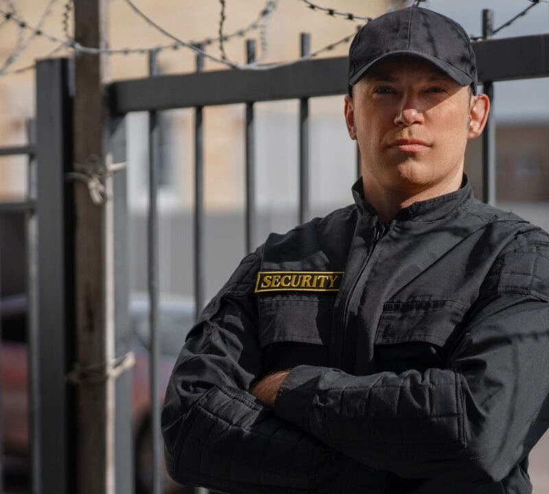 Portrait of male security guard with barbed wire fence