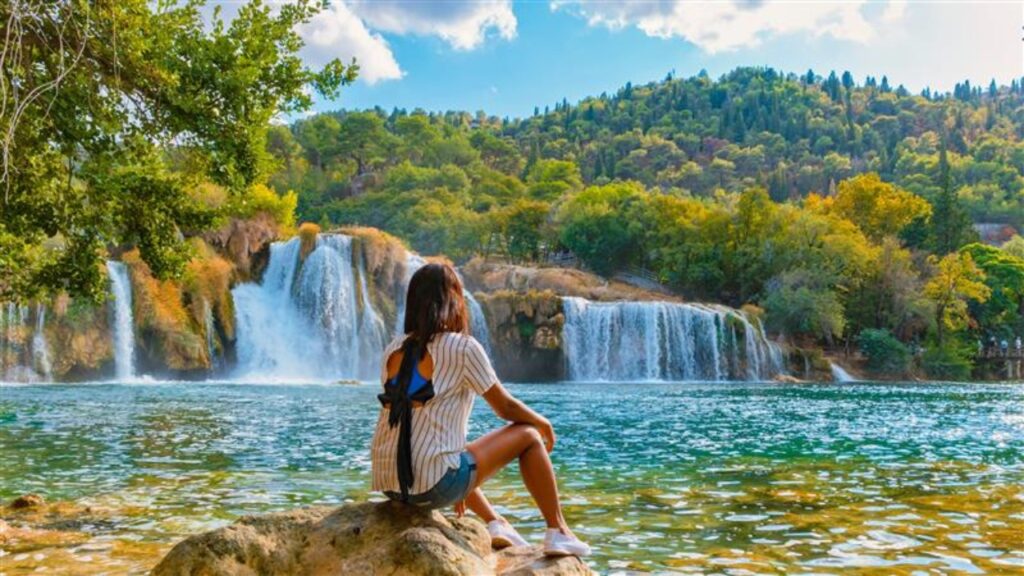 KRKA waterfalls Croatia during summer, young Asian women watch the waterfalls of krka national park Croatia on a bright summer evening in the park