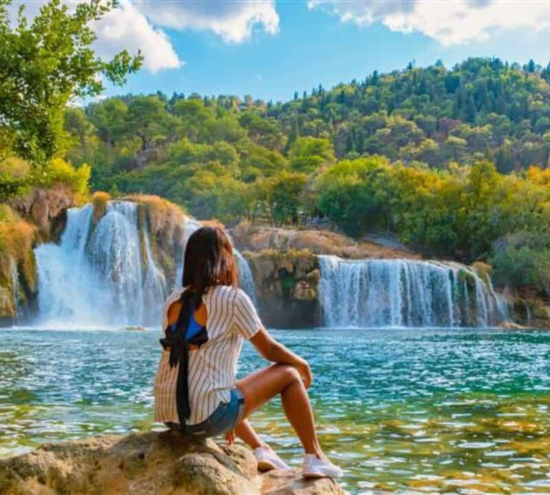 KRKA waterfalls Croatia during summer, young Asian women watch the waterfalls of krka national park Croatia on a bright summer evening in the park
